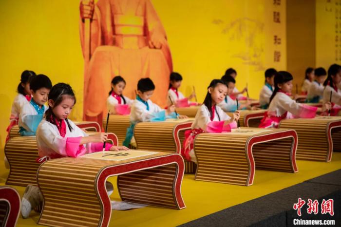 2021年4月10日,辛丑年澳门恭拜轩辕黄帝大典在澳门旅游塔会议中心举行。图为身穿汉服的澳门小学生在书写毛笔字。中新社发 钟欣 摄